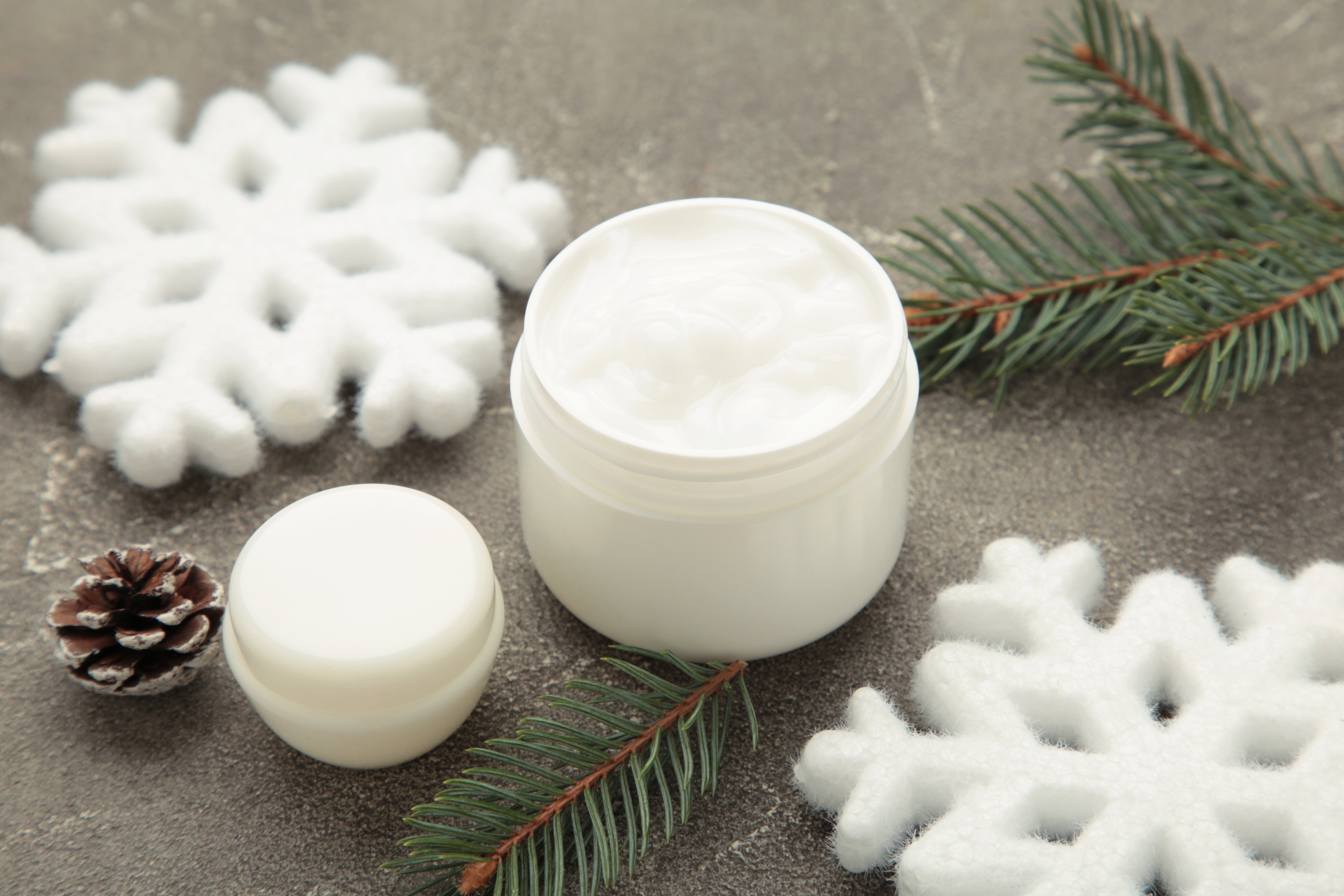 Winter Gesichtscreme Kosmetik mit Schneeflocken umgeben